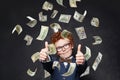 Funny kid boy showing thumb up under us dollar money rain on black background Royalty Free Stock Photo