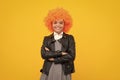 Funny kid in curly redhead wig. Time to have fun. Teen girl with orange hair, being a clown. Happy girl face, positive Royalty Free Stock Photo