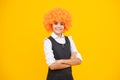 Funny kid in curly redhead wig. Time to have fun. Teen girl with orange hair, being a clown. Happy girl face, positive Royalty Free Stock Photo