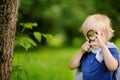 Funny kid exploring nature with magnifying glass.