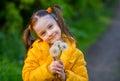 Funny kid girl with ponytails in a yellow jacket holds white fluffy dandelions and smiles Royalty Free Stock Photo