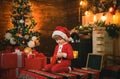 Funny kid holding Christmas gift. Child with gift. Models child having fun with gift. Kid having fun near Christmas tree Royalty Free Stock Photo