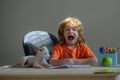 Funny Kid home learning. Excited child and pet dog playing at home. Pupil with puppy doing school homework.