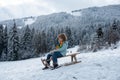 Funny kid in snow ride on sled, sleigh. Winter outdoors games. Happy Christmas family vacation concept. Child sledging Royalty Free Stock Photo