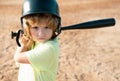 Funny kid up to bat at a baseball game. Close up child portrait.