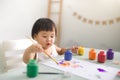 Funny laughing asian baby girl drawing with colorful pencils at Royalty Free Stock Photo