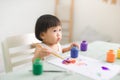 Funny laughing asian baby girl drawing with colorful pencils at Royalty Free Stock Photo