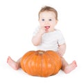 Funny laughing baby girl playing with huge pumpkin