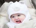 Funny laughing baby in a teddy bear hat in stroller Royalty Free Stock Photo