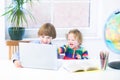 Funny laughing kids playing together with a laptop