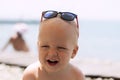 Funny laughing toddler in sunglasses on the sea. Little boss on vacation