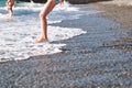 Funny legs of a girl and boy on the beach run away and jump into the sea waves at sunset Royalty Free Stock Photo