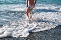 Funny legs of a girl and boy on the beach run away and jump into the sea waves at sunset Royalty Free Stock Photo