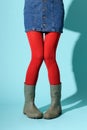 Funny legs of a young woman in red collant and green rubber boot