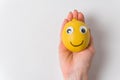 Funny lemon fruit character lies in female hand on white background. Cheerful fruit with eyes and smile