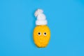 A funny lemon in a hat with a pom-pom and eyes isolated on blue background. Winter holidays or ugly fruit concept