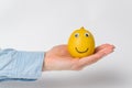 Funny lemon-smiley with Googly eyes lying on palm. White background