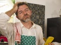 Funny lifestyle portrait of mid adult unhappy and stressed man in kitchen apron feeling frustrated and upset overwhelmed by Royalty Free Stock Photo