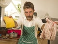 Funny lifestyle portrait of mid adult unhappy and stressed man in kitchen apron feeling frustrated and upset overwhelmed by Royalty Free Stock Photo