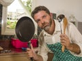 Funny lifestyle portrait of mid adult unhappy and stressed man in kitchen apron feeling frustrated and upset overwhelmed by Royalty Free Stock Photo