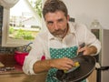Funny lifestyle portrait of mid adult unhappy and stressed man in kitchen apron feeling frustrated and upset overwhelmed by Royalty Free Stock Photo