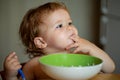 Funny little baby in the kitchen eating with fingers from plate. Child nutrition concept. Royalty Free Stock Photo