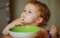 Funny little baby in the kitchen eating with fingers from plate. Child nutrition concept. Royalty Free Stock Photo