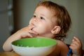 Funny little baby in the kitchen eating with fingers from plate. Child nutrition concept. Royalty Free Stock Photo