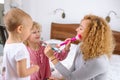 Funny little blond girl putting makeup on her mother`s face Royalty Free Stock Photo