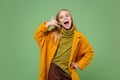 Funny little blonde kid girl 12-13 years old in yellow coat posing isolated on pastel green background. Childhood Royalty Free Stock Photo