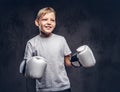 Funny little boy boxer with blonde hair dressed in a white t-shirt wearing boxing gloves posing in a studio. Isolated on Royalty Free Stock Photo