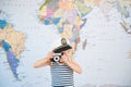 Funny little boy in captain hat taking picture by old retro film camera near map Royalty Free Stock Photo