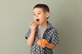Funny little boy eating citrus fruit on color background Royalty Free Stock Photo
