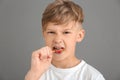 Funny little boy eating lollipop on grey background Royalty Free Stock Photo