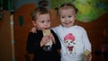 Funny little boy and girl drinking juice together in kindergarten