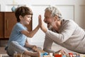 Funny little boy giving high five to joyful older grandfather. Royalty Free Stock Photo