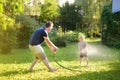 Funny little boy with his father playing with garden hose in sunny backyard. Preschooler child having fun with spray of water Royalty Free Stock Photo