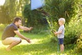 Funny little boy with his father playing with garden hose in sunny backyard. Preschooler child having fun with spray of water Royalty Free Stock Photo