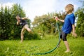 Funny little boy with his father playing with garden hose in sunny backyard. Preschooler child having fun with spray of water. Royalty Free Stock Photo