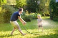 Funny little boy with his father playing with garden hose in sunny backyard. Preschooler child having fun with spray of water Royalty Free Stock Photo
