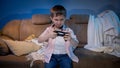 Funny little boy holding game controller while playing video games on TV console at night Royalty Free Stock Photo