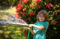 Funny little boy playing with garden hose in backyard. Child having fun with spray of water. Summer outdoors activity Royalty Free Stock Photo