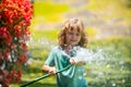 Funny little boy playing with garden hose in backyard. Child having fun with spray of water on yard nature background Royalty Free Stock Photo