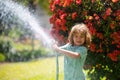 Funny little boy playing with garden hose in backyard. Child having fun with spray of water on yard nature background Royalty Free Stock Photo