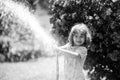 Funny little boy playing with garden hose in backyard. Child having fun with spray of water on yard nature background Royalty Free Stock Photo