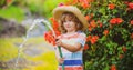 Funny little boy playing with garden hose in backyard. Child having fun with spray of water on yard nature background Royalty Free Stock Photo