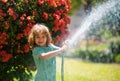 Funny little boy playing with garden hose in backyard. Child having fun with spray of water on yard nature background Royalty Free Stock Photo