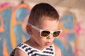 Funny little boy wearing sunglasses and sailor shirt on graffiti background Royalty Free Stock Photo