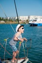 Funny little captain boy shouting from sea yacht board in harbor port during arrival in destination resort