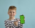 Funny little caucasian kid boy 9s years old in basic striped shirt hold mobile cell phone. Royalty Free Stock Photo